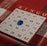 A bingo card is placed on a red and white plaid tablecloth. The card has columns labeled B, I, N, G, and O, each filled with numbers. A blue transparent marker is placed on the number 22 under the N column.